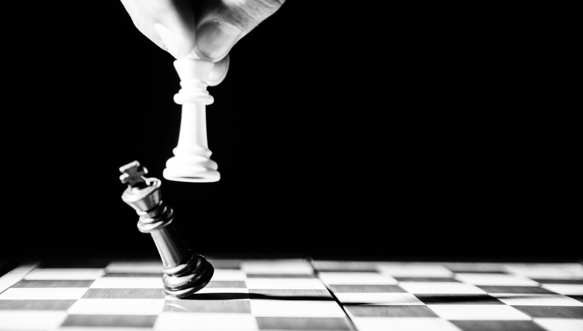 White king chess piece knocking down a black king piece