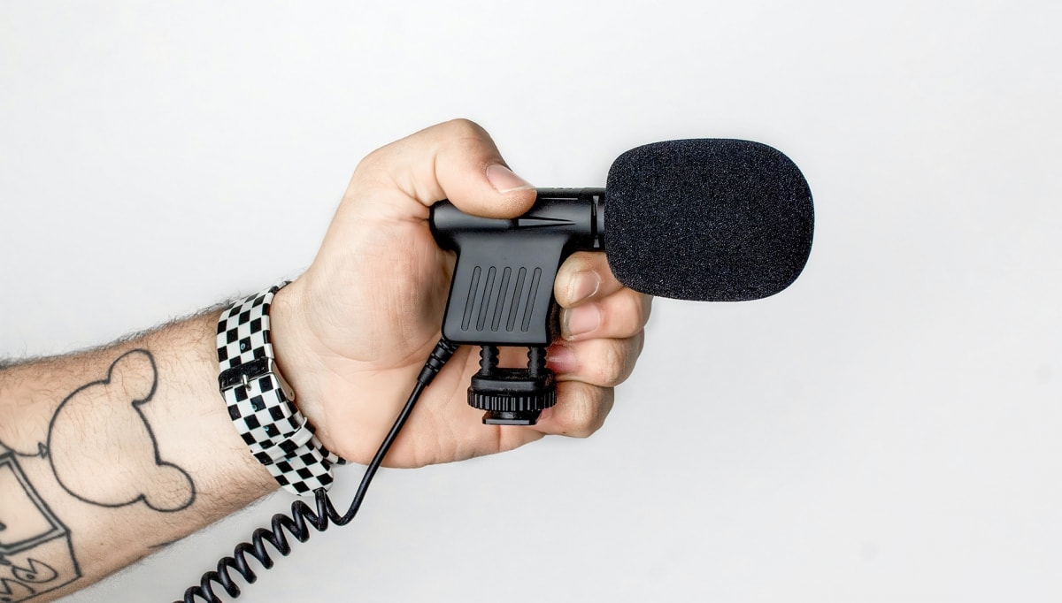 Hand microphone on a man's hand with tattoos and black-and-white wrist watch
