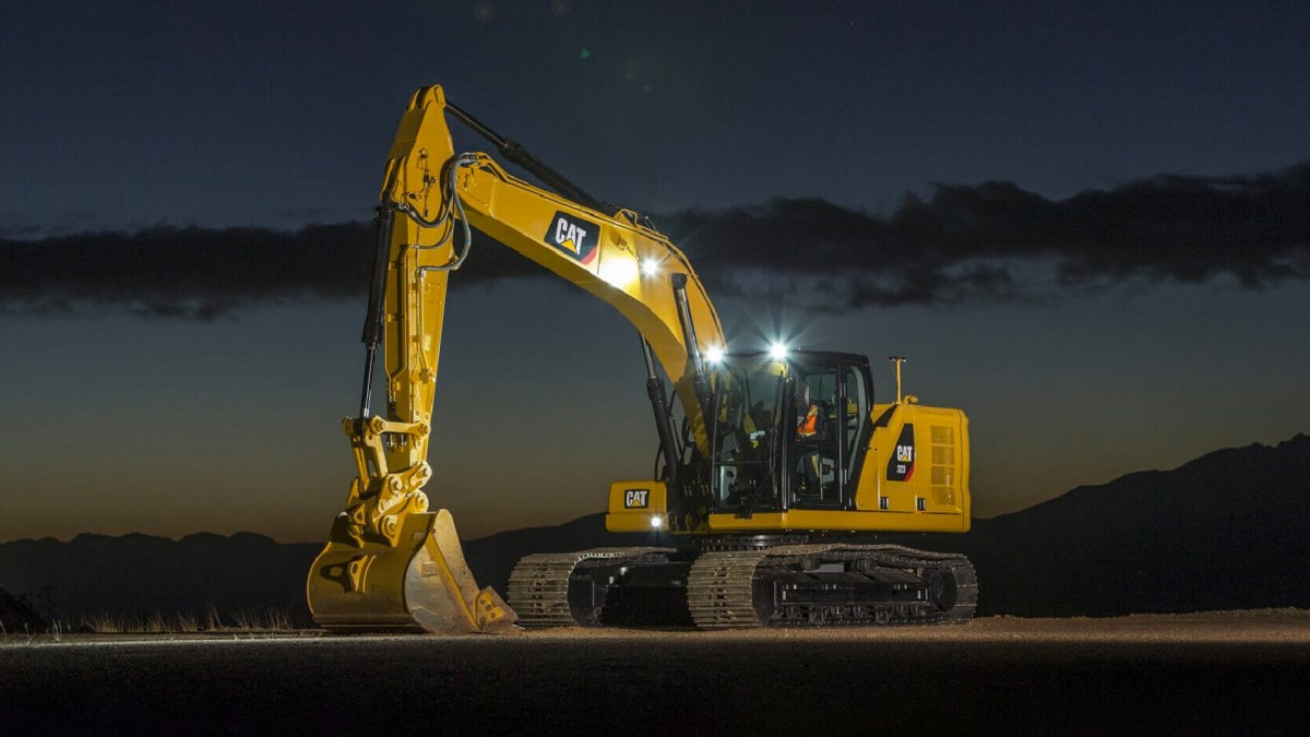 Yellow Caterpillar hydraulic shovel at night time with headlights on